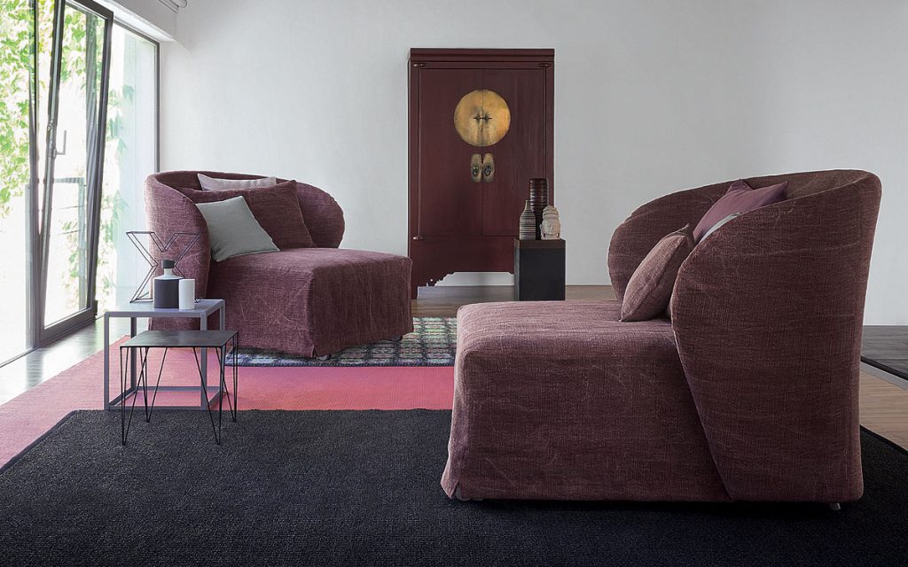 Two Celine Armchair Sleepers in purple. White, gray and purple pillows and wheels in a bedroom.