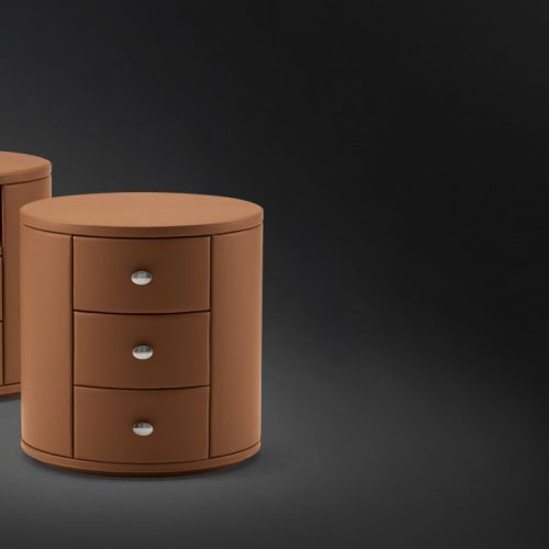 Two Condotti round night table with two or three drawers covered in orange leather on a black background.