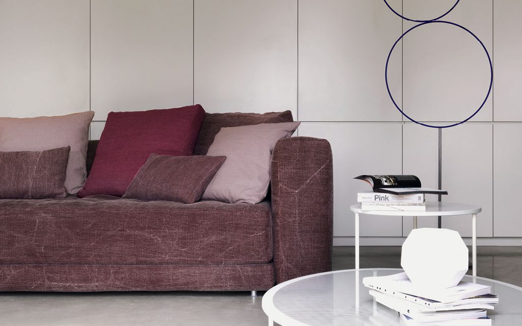 Closeup of Doze composition A sofa made of purple fabric with legs in a living room.