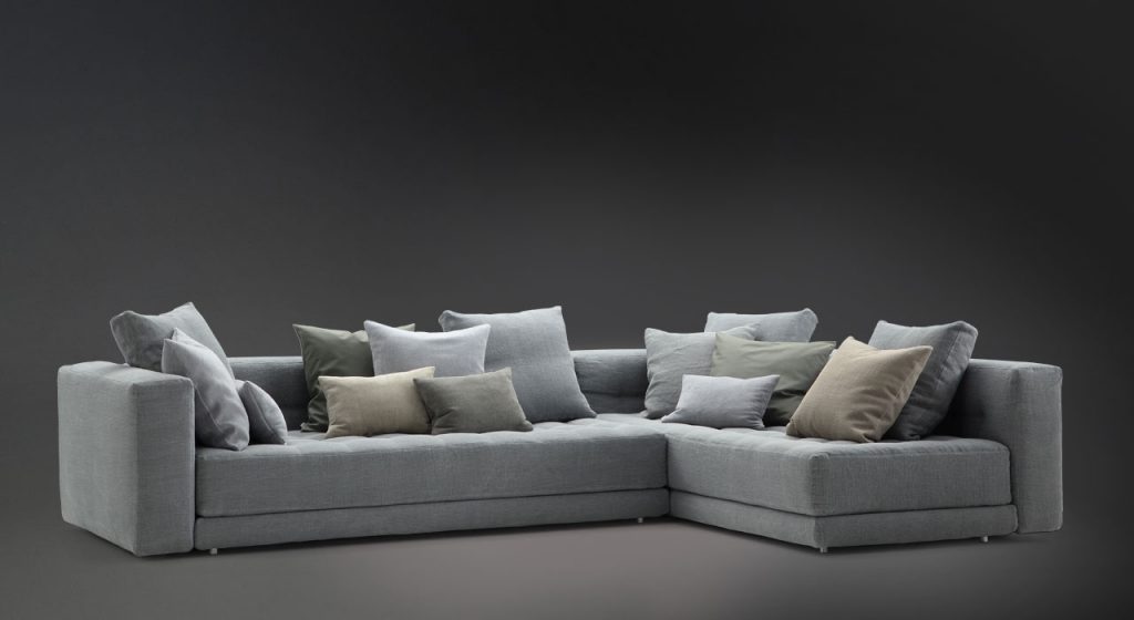 Short L shaped Doze composition B sofa made of gray fabric with legs on a black background.