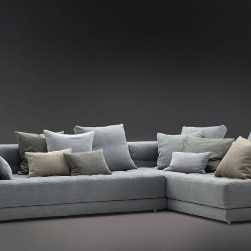 Short L shaped Doze composition B sofa made of gray fabric with legs on a black background.