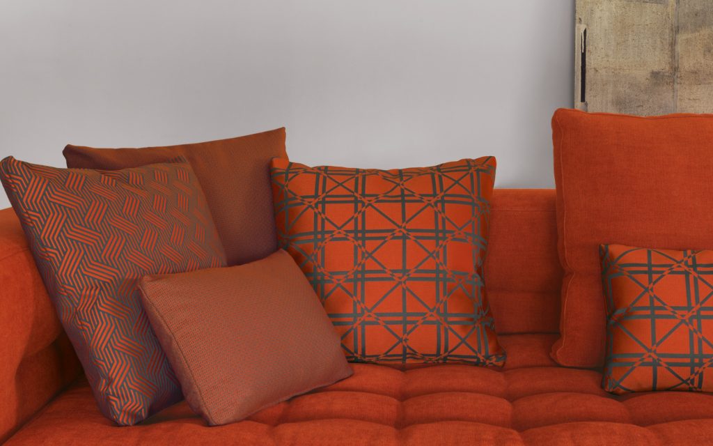 Closeup of Short L shaped Doze composition B sofa made of red fabric with legs in a living room.