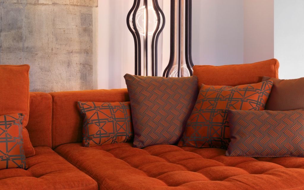Closeup of Short L shaped Doze composition B sofa made of red fabric with legs in a living room.