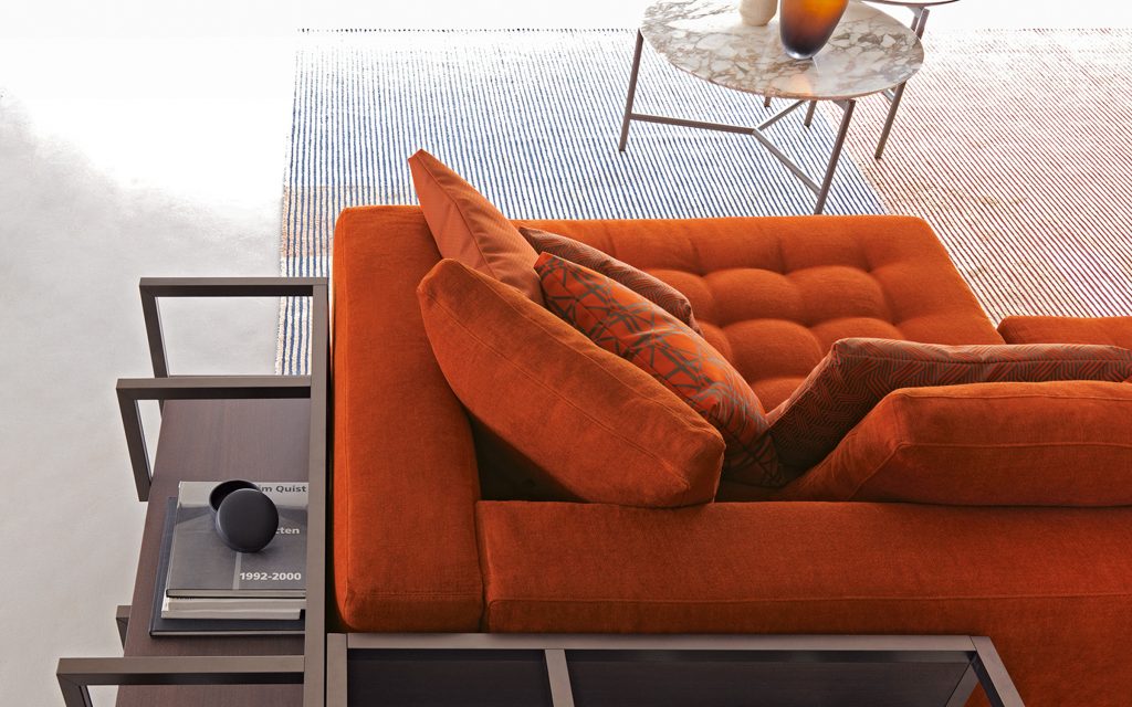 Closeup of Short L shaped Doze composition B sofa made of red fabric with legs in a living room.