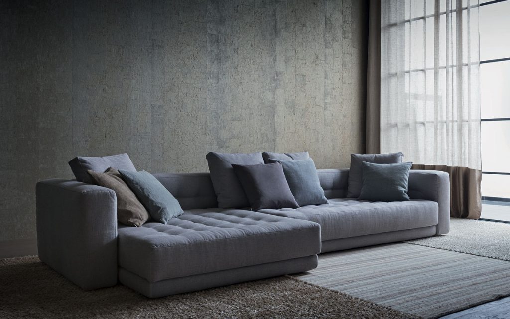 Short L shaped Doze composition B sofa made of gray fabric with legs in a living room.