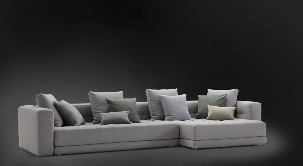 Short L shaped Doze composition D sofa made of gray fabric with legs on a black background.