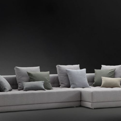 Short L shaped Doze composition D sofa made of gray fabric with legs on a black background.