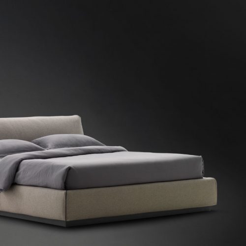 Gentleman Low. Base and headboard upholstered in gray fabric with bedding on a black background.