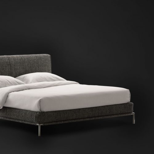 Icon bed. Base and heardboard padded in gray fabric with black steel legs on a black background.