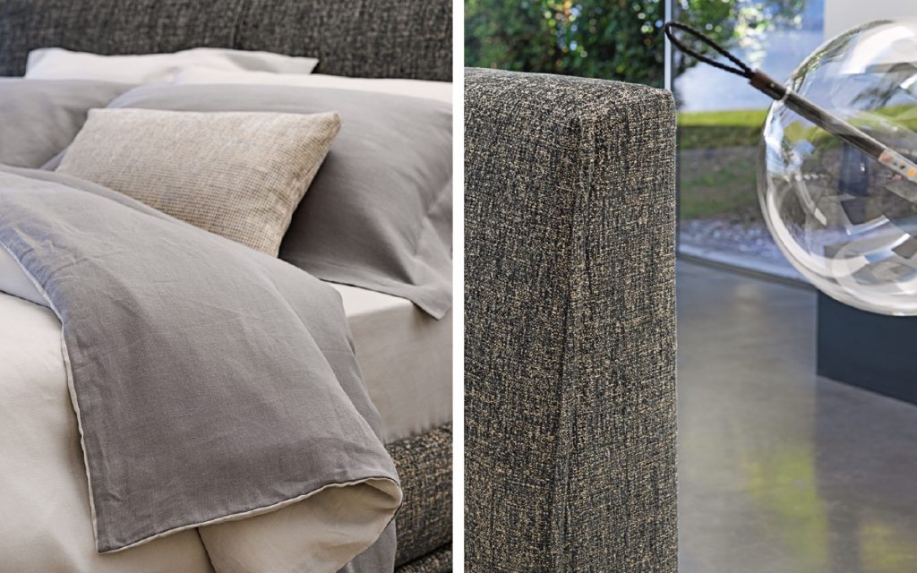Closeup of Icon bed. Base and heardboard padded in gray fabric with black steel legs in a bedroom.