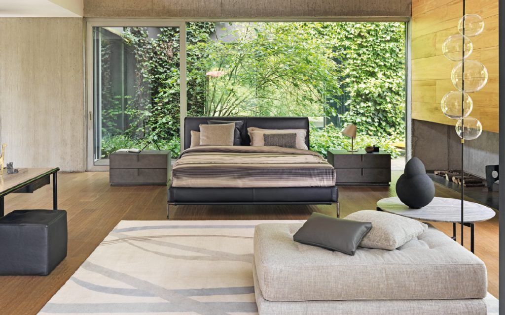 Icon bed. Base and heardboard padded in black leather with black steel legs in a bedroom.