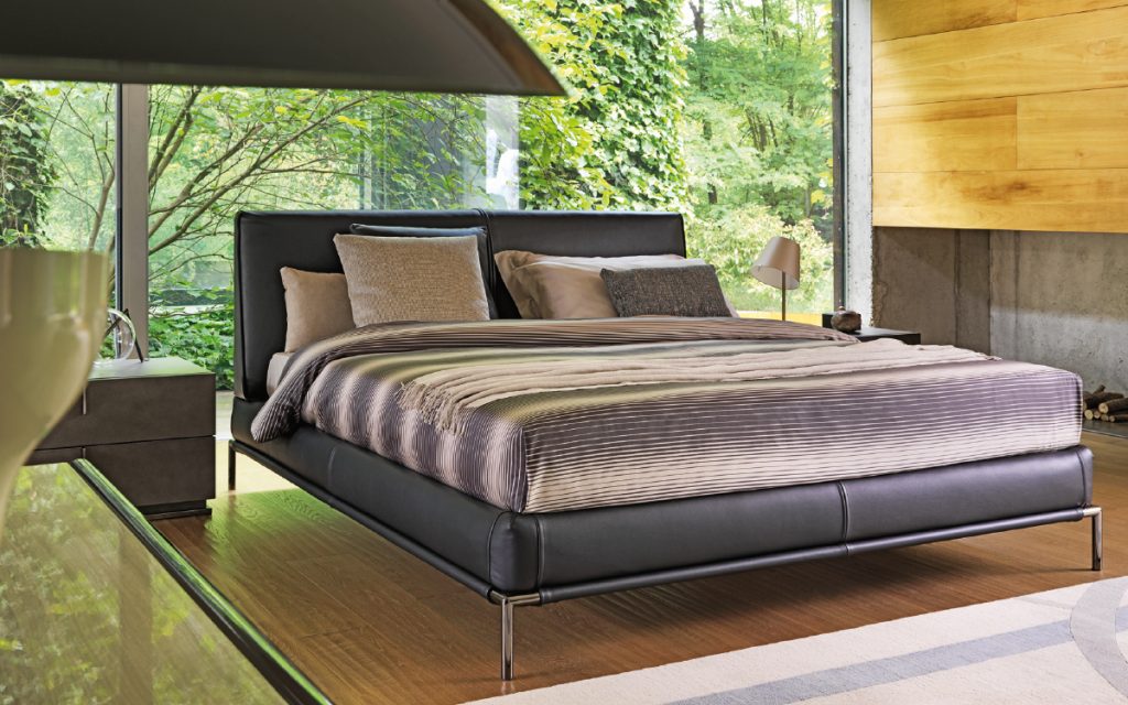 Icon bed. Base and heardboard padded in black leather with black steel legs in a bedroom.