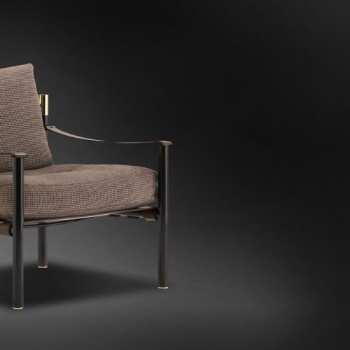 Iko Armchair. Black structure and legs with gold details. Brown cushion covers on a black background.