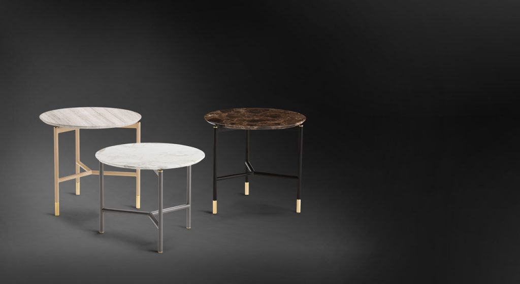 Iko Side Table. Round top in white, gray and brown, legs in gold, silver and black on a black background.
