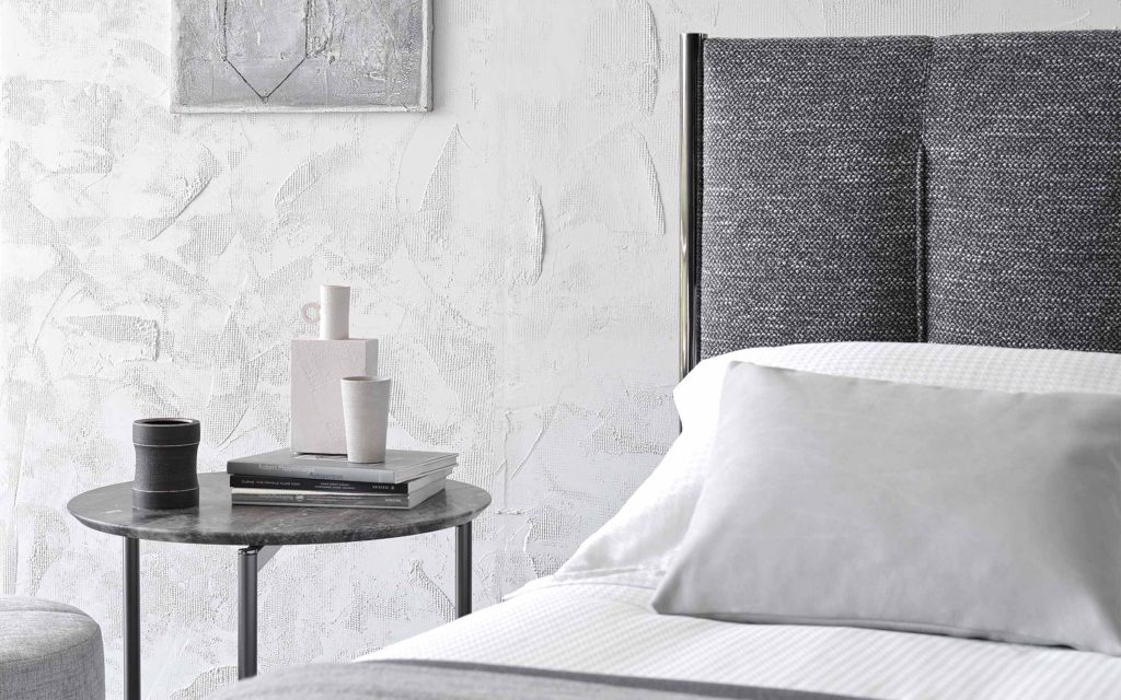 Closeup of Koi double size bed upholstered in gray fabric, heardboard with vertical lines pattern.