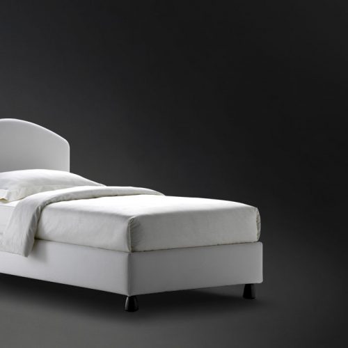 Magnolia Single bed. Padded headboard and base with white fabric and black legs on a black background.