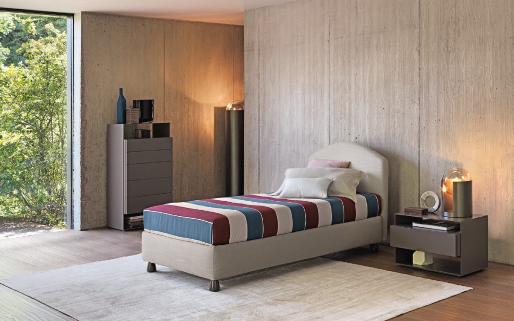 Magnolia Single bed. Padded headboard and base with white fabric and black legs in a bedroom.