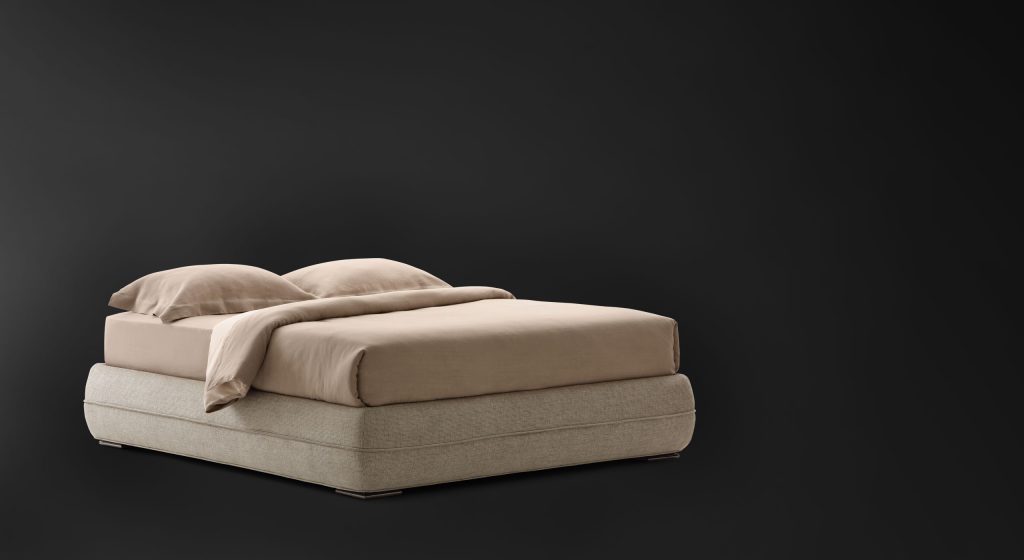 Mandarin Sommier in gray fabric and a mattress with bedding on a black background.