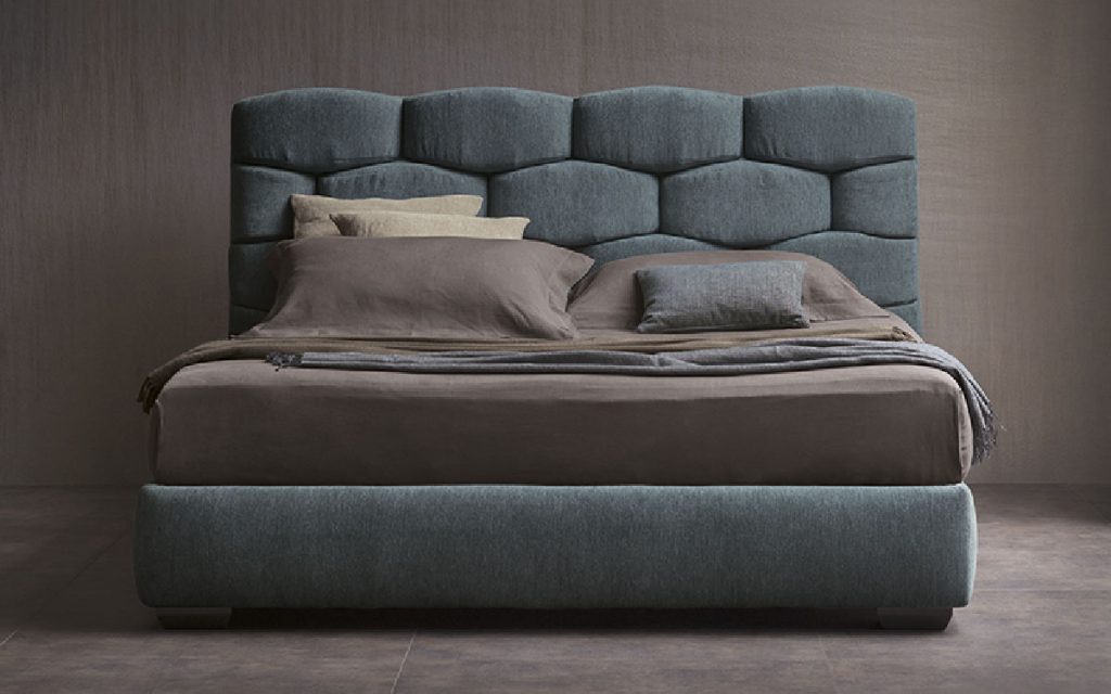 Blue Majal Double bed. Geometric shapes on the headboard and bedding in a bedroom.