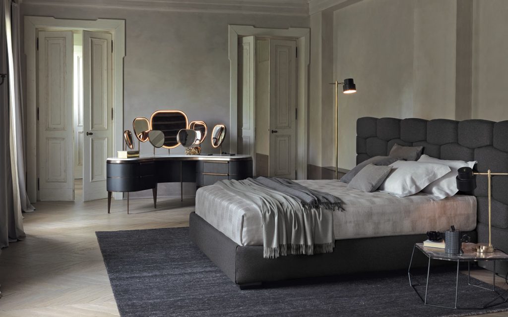 Gray Majal wide bed with geometric shapes on the headboard, mattress and bedding in a bedroom.