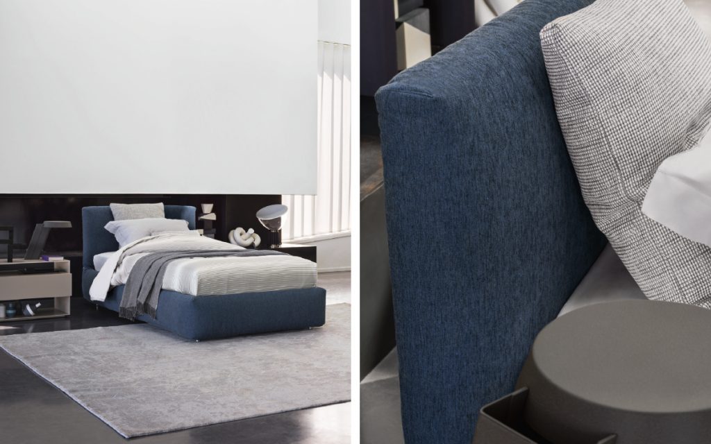 Closeup of Merkurio Single bed. Base and headboard upholstered in blue fabric with four legs in a bedroom.