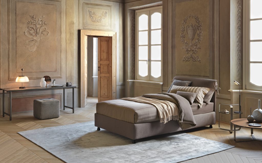 Nathalie Single bed brown headboard cushions and brown base with black legs and bedding in a bedroom.