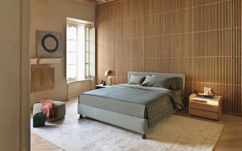Notturno 2 Double bed. Base and backrest covered in gray fabric and bedding in a bedroom.
