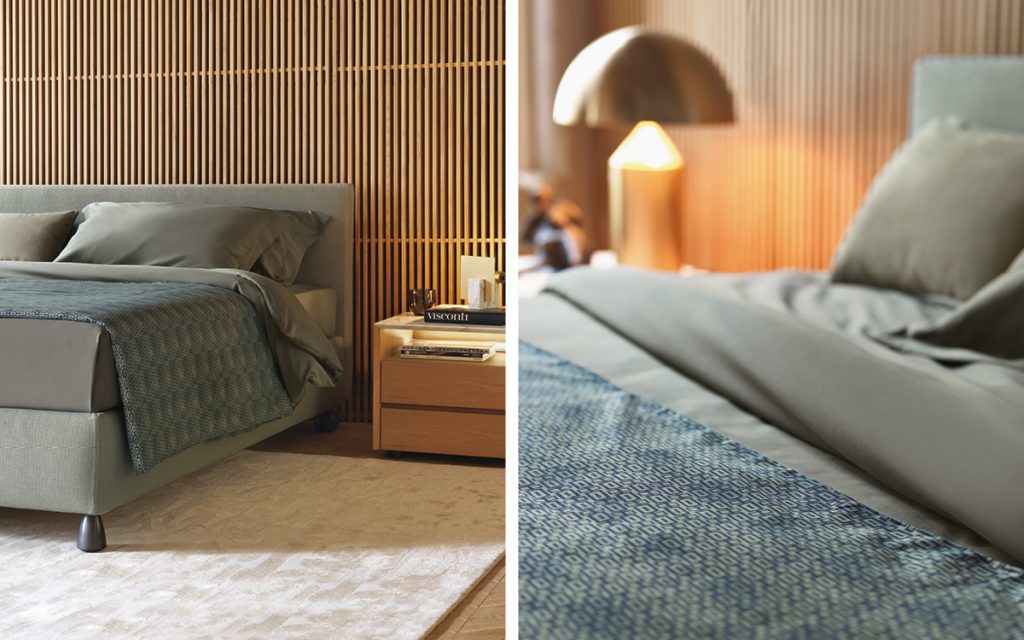 Closeup of Notturno 2 Double bed. Base and backrest covered in gray fabric and bedding in a bedroom.