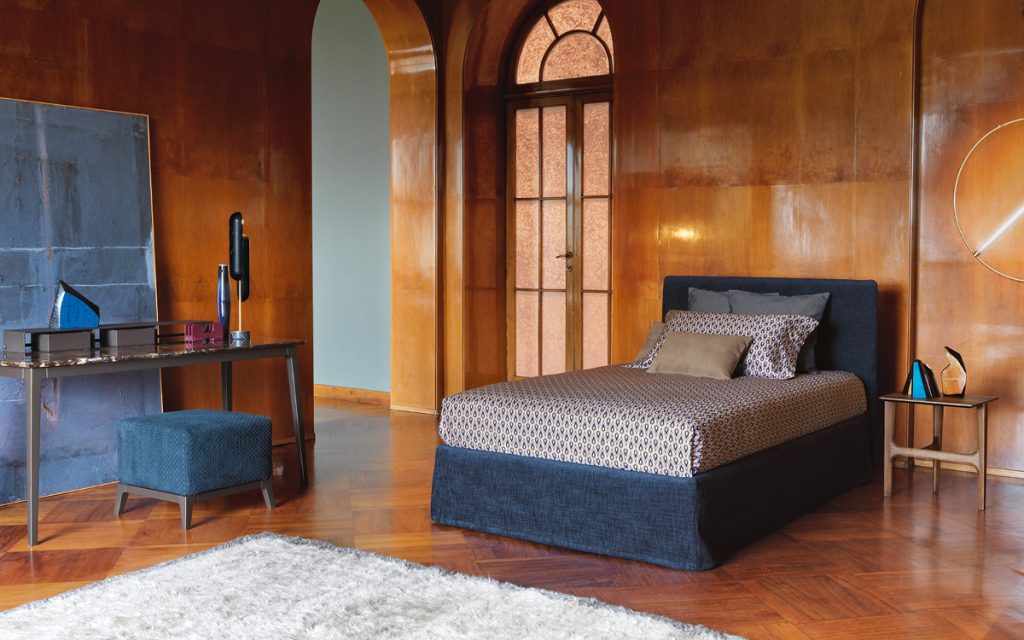 Notturno Shabby Chic Bed. Base and backrest covered in blue fabric with bedding in a bedroom.
