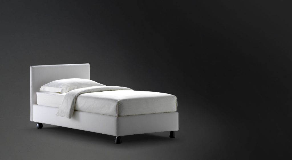 Notturno Single bed. Base and backrest covered in gray fabric and legs on a black background.