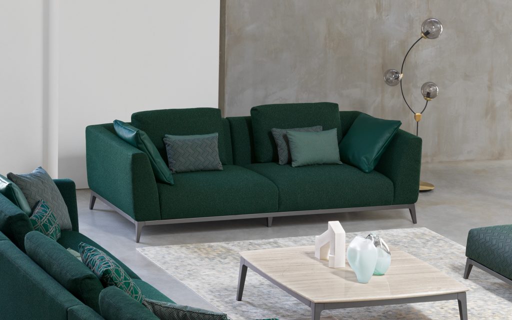 Two Olivier C sofas upholstered in green fabric and four legs in steel in a living room.