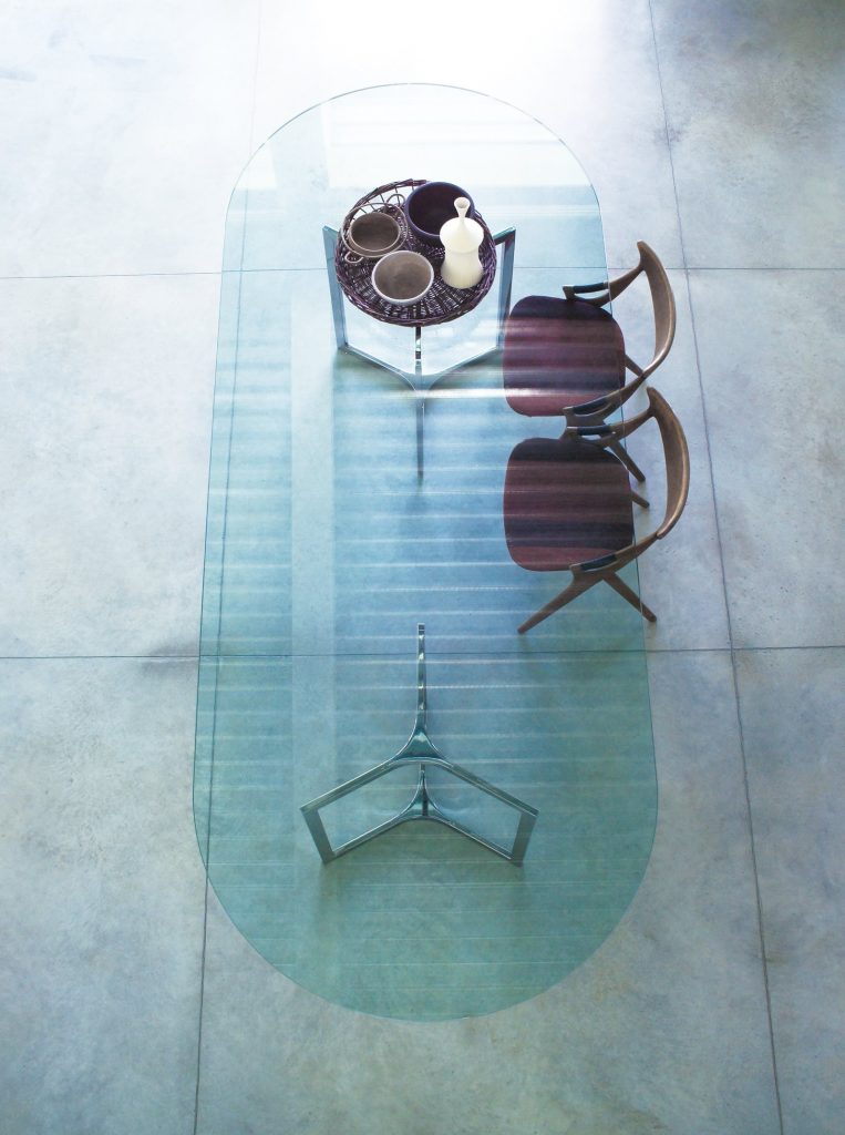 Raj / Raj Light Home: Large oval dining table with a glass top and silver metal frame in an office.