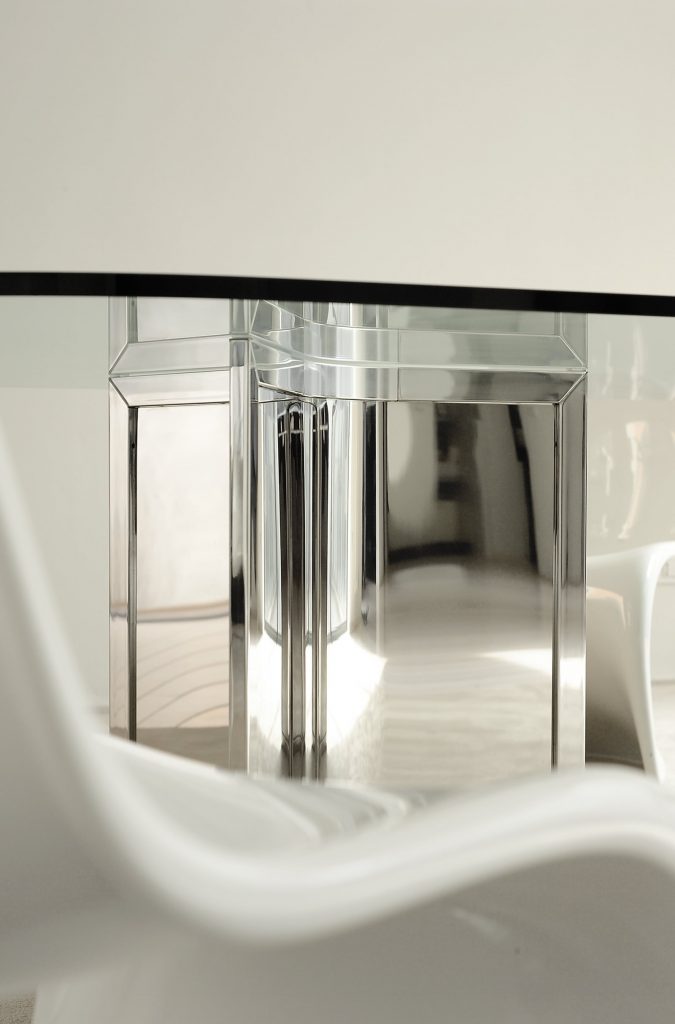 Closeup of Raj / Raj Light Office: Large oval table with a glass top and silver metal frame in an office.