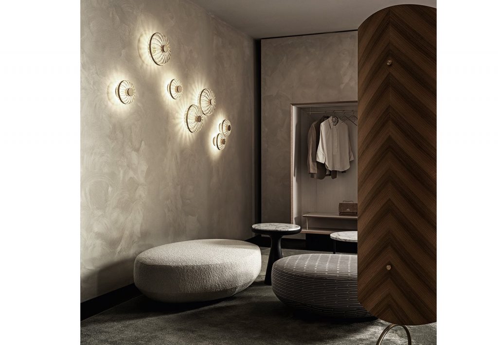 Shield screen composed by 4 curved wooden modules. Satin brass structure and accessories with bevelled mirrors in a bedroom.