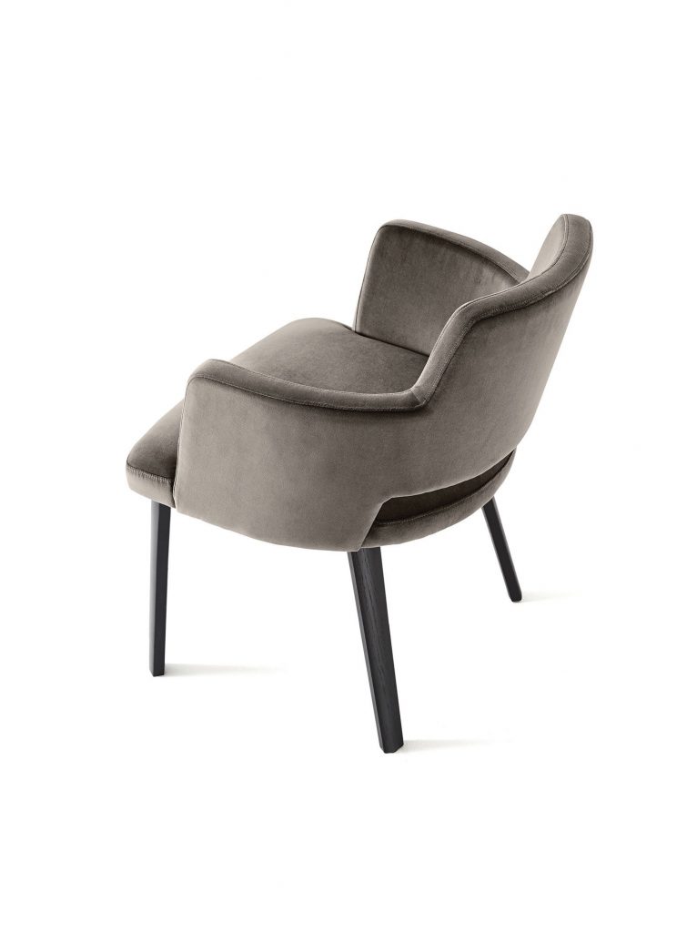 Thea Queen: A beige, tufted armchair with black wooden legs on a white background.