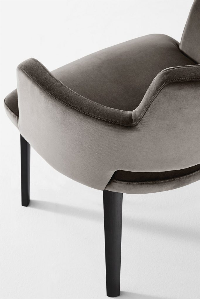 Thea Queen: A beige, tufted armchair with black wooden legs on a white background.