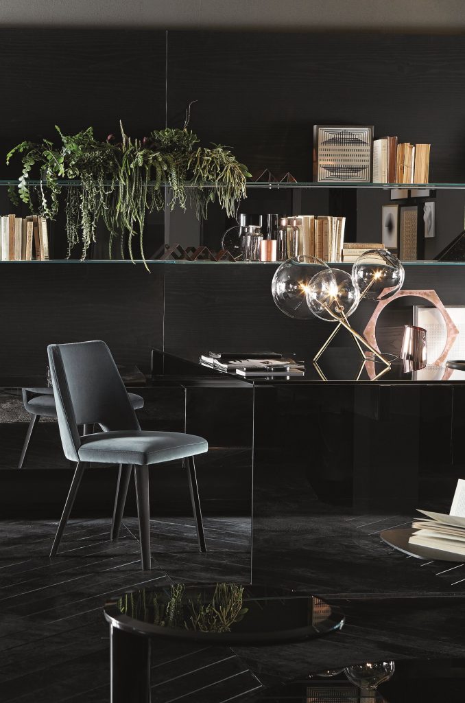 Thea: A gray chair with a curved backrest and four black legs in a living room.
