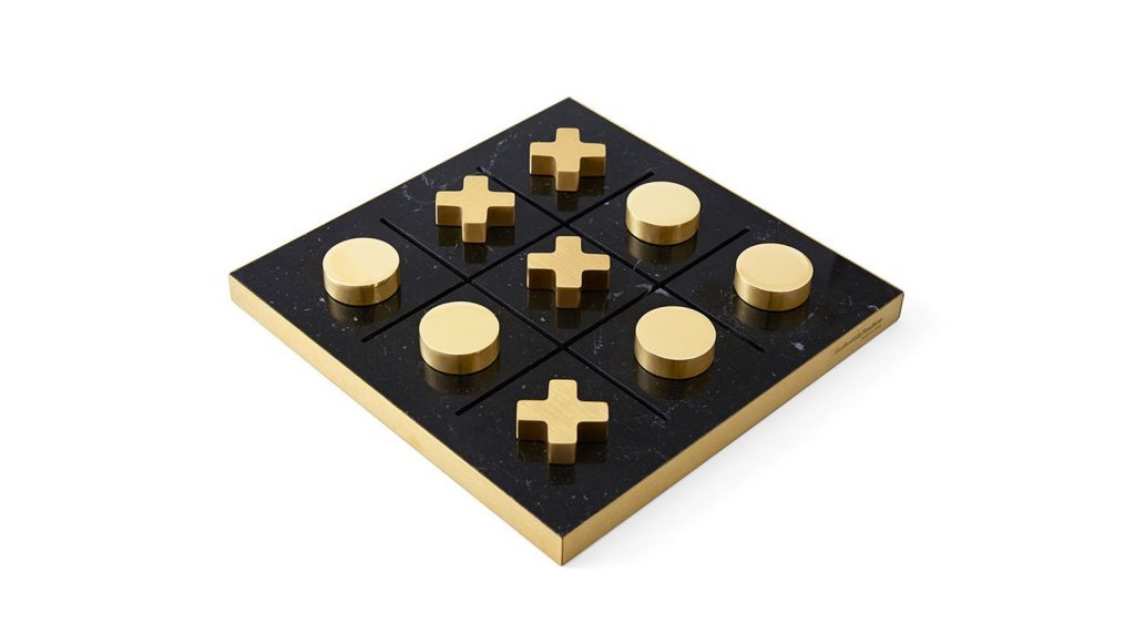 Tip Tap Toe square table game. Base in black and gold , pieces in gold on a white background.