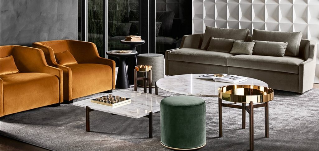 Four Twelve coffee tables. Two golden round tops and two in marble. one in round and one in square shape with three bronze legs in a living room.