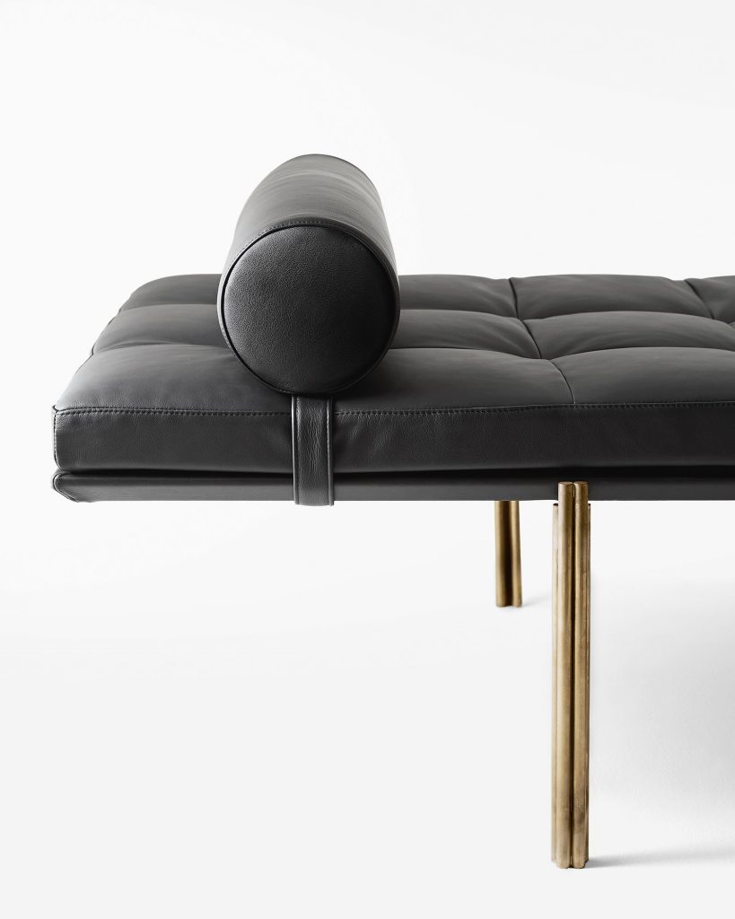 Rectangular Twelve Daybed upholstered in black fabric with rectangular pattern and four gold legs on a white background.