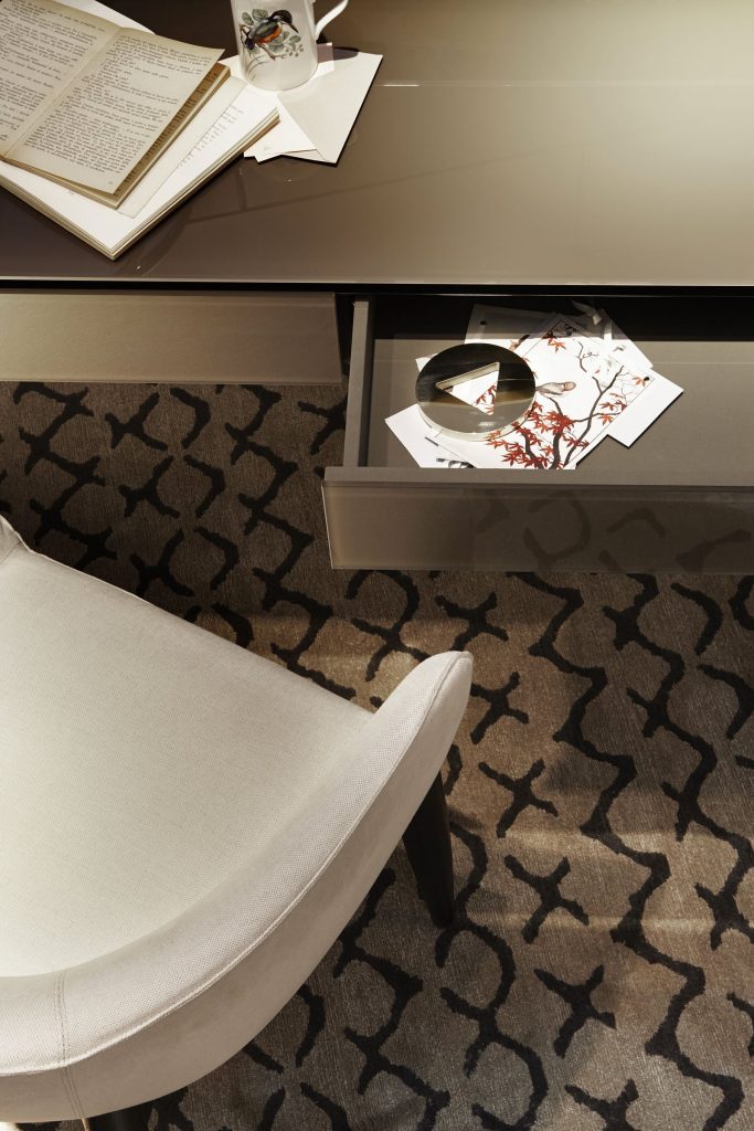 Venere wooden desk featuring a beige top and slender black legs in an office.