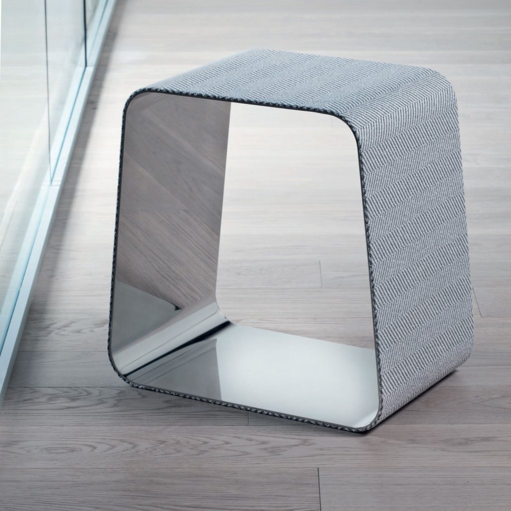 WGS stool with a rectangle shape. Internal part in silver and external part in white and black zig zag pattern on a brown background.