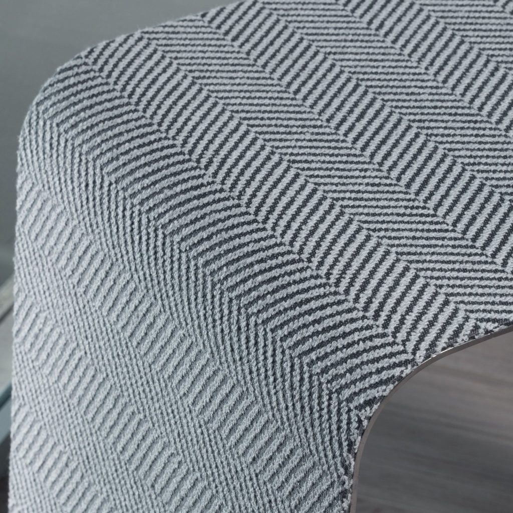 WGS stool with a rectangle shape. Internal part in silver and external part in white and black zig zag pattern on a brown background.