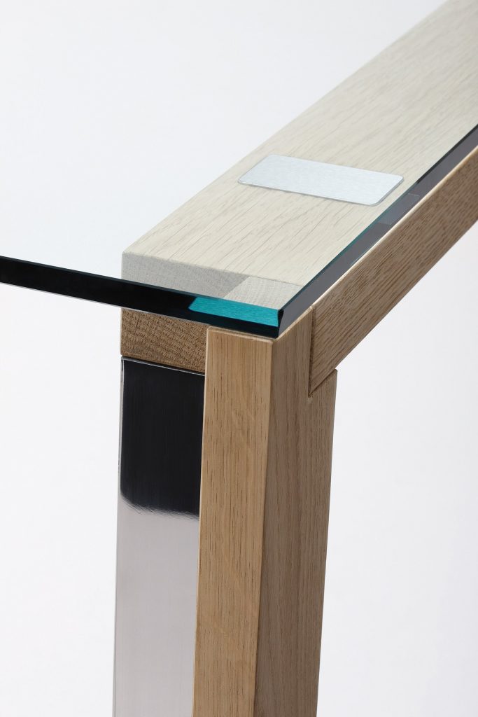 WGS table with crystal rectangle top eaturing wooden legs and a sleek metal frame on a white background.