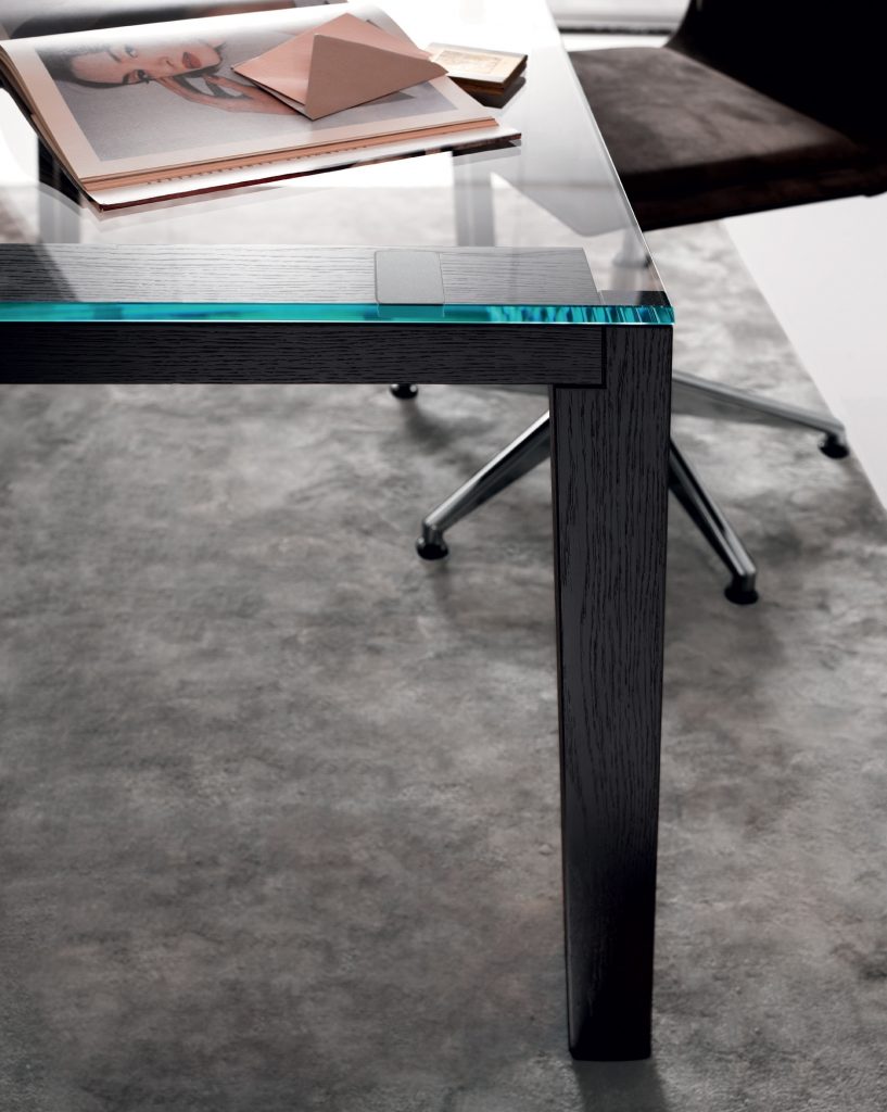 WGS table with crystal rectangle top eaturing wooden legs and a sleek metal frame in an office.