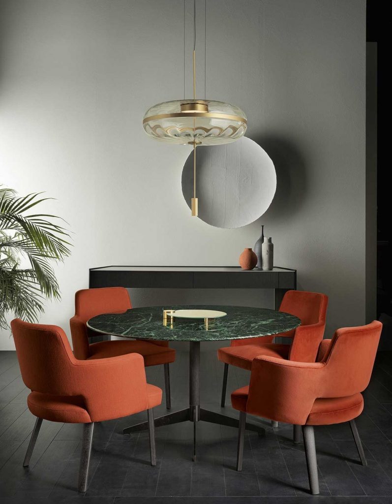 Zen Black table, round top in green and black marble and central black leg in a dining room.