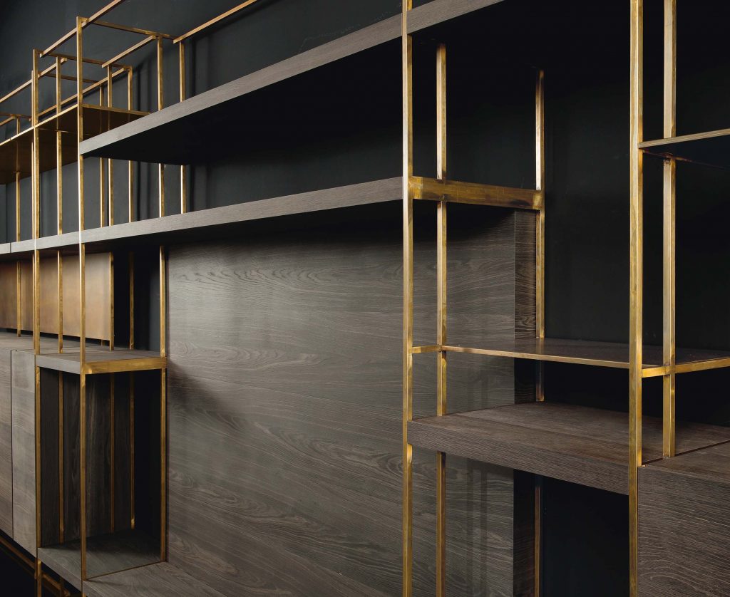 Closeup of Cage C shelves with wood drawer and finish in brass on a black background.