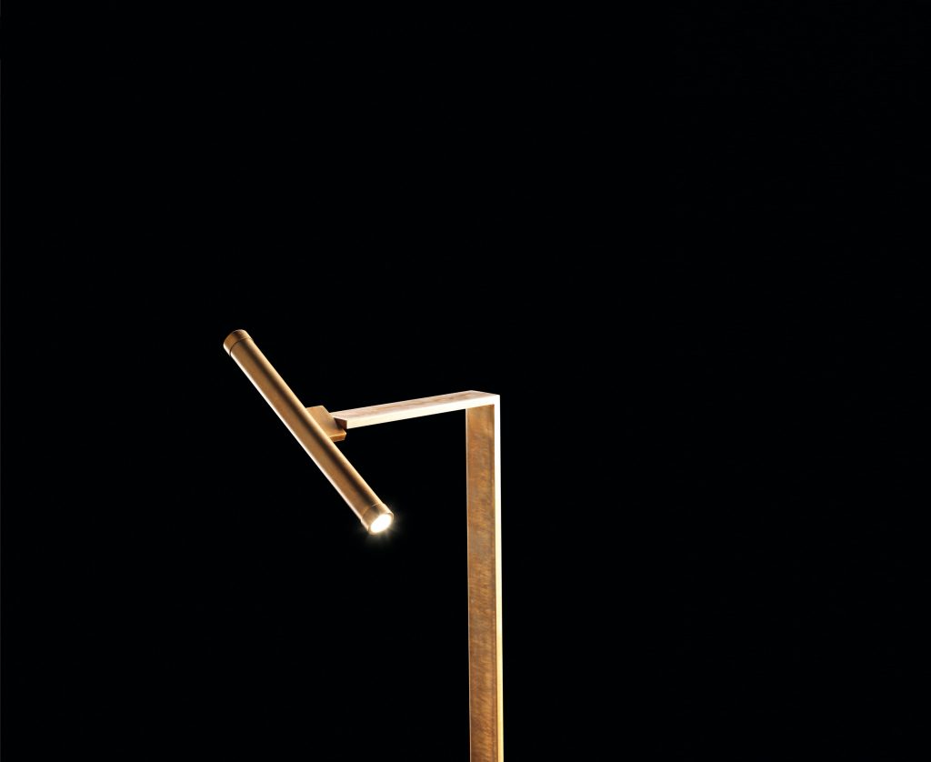 Let Flat Lamps with brass pipe structure, multi directional light, power lead with red silk cover, counterweight in stone on a black background.