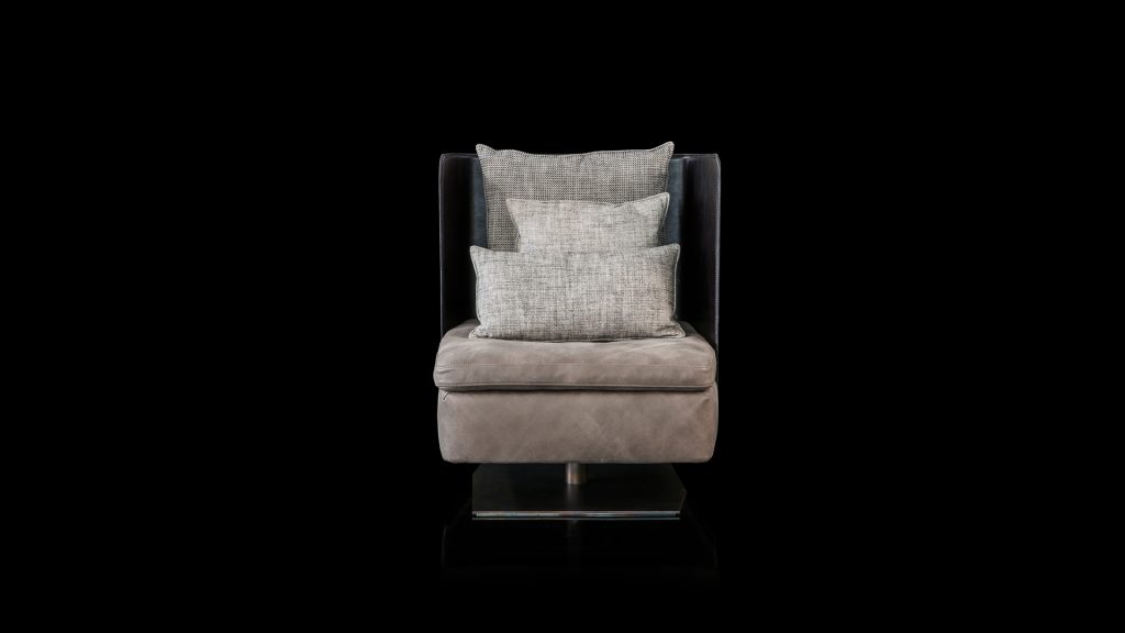 Human Armchair upholstered in brown leather and three gray cushions. Structure armchair with metal base frame and central leg on a black background.
