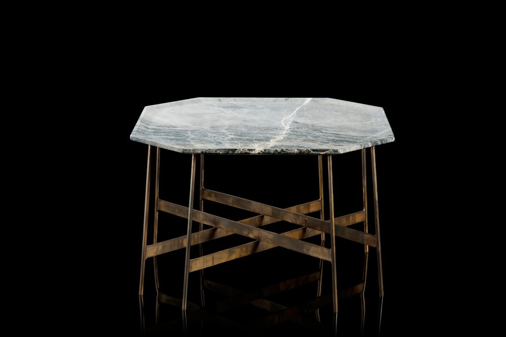 Octagon Table, finish structure and eight legs in burnished brass, top in white and gray stone on a black background.
